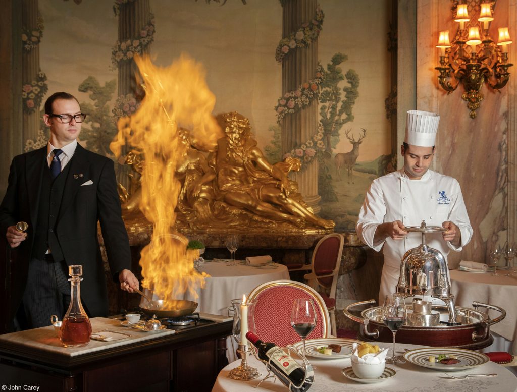 Waiter and chef Flambé at an elegant dining table at the Hotel Ritz.